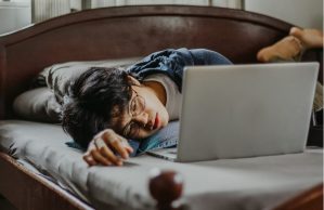 A high school student lies on his bed instead of doing school work.